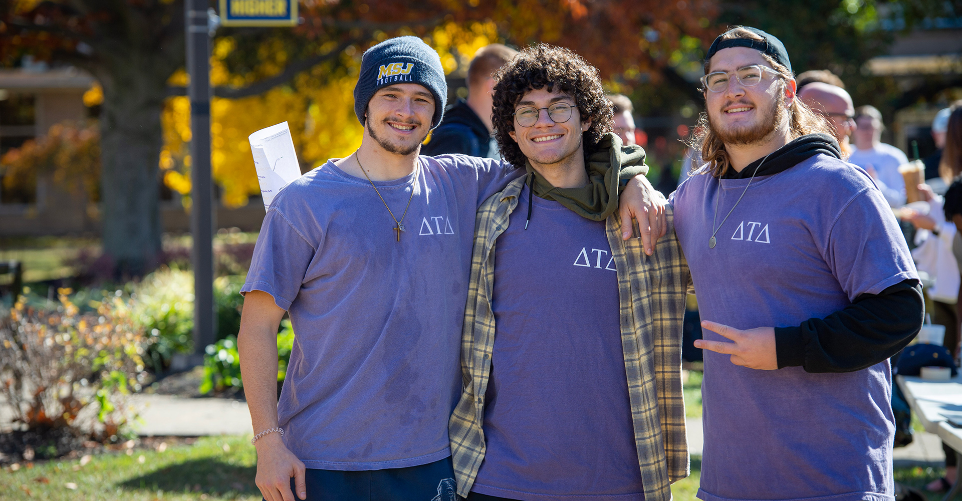 MSJ male students in greek life shirts with arms around each other in quad smiling.