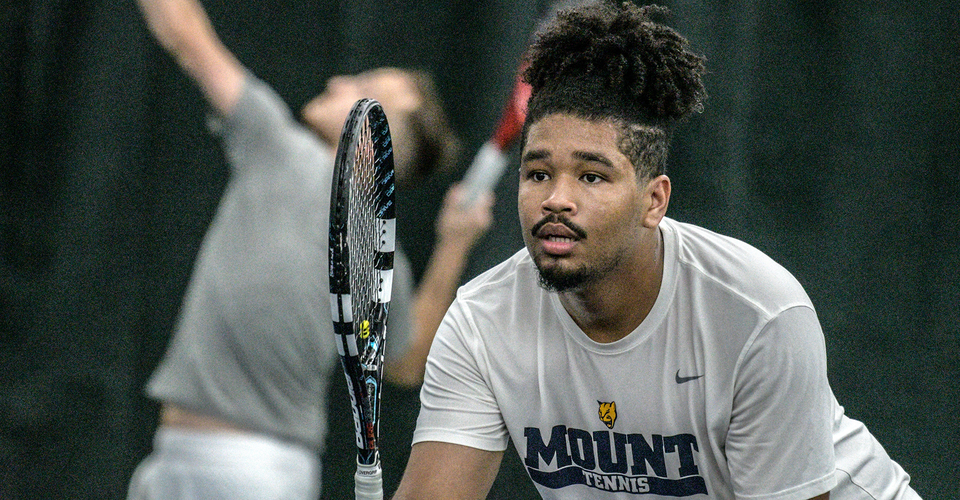 MSJ male tennis player with tennis racket held up.