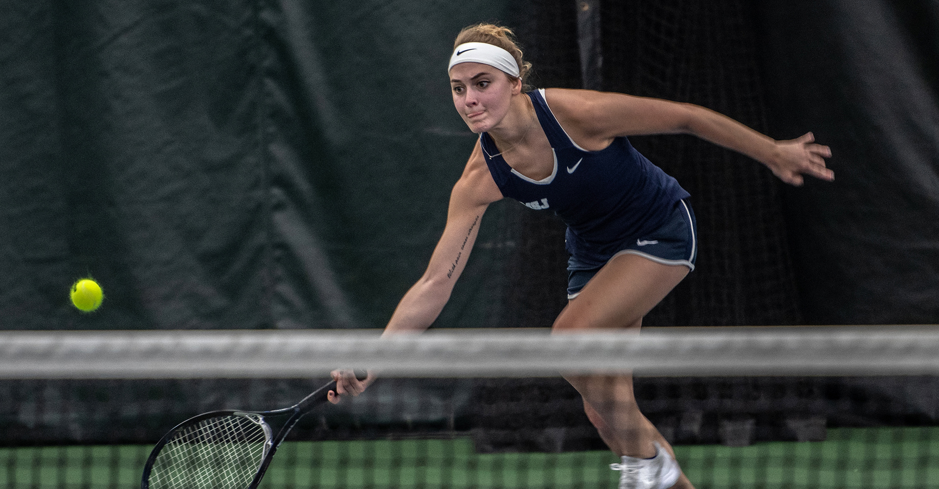 MSJ female tennis player hitting ball with racket.