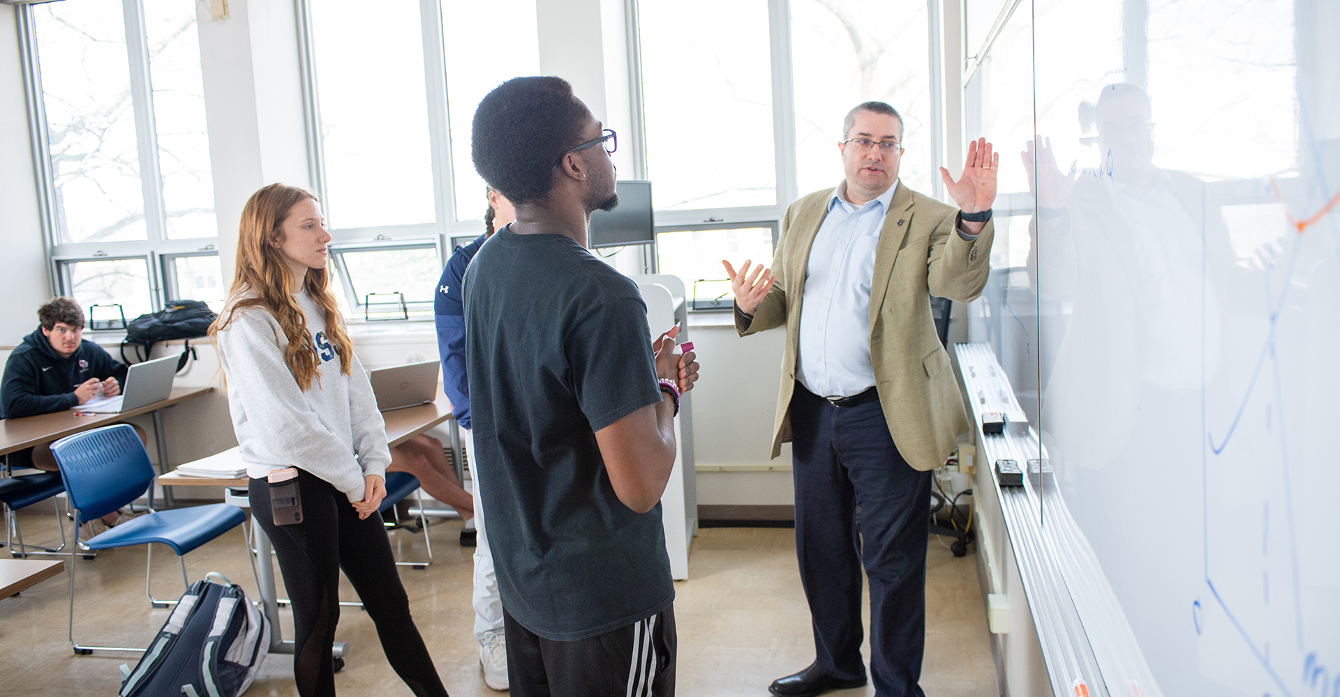 MSJ business professor charles kroncke teaching finance students on whiteboard