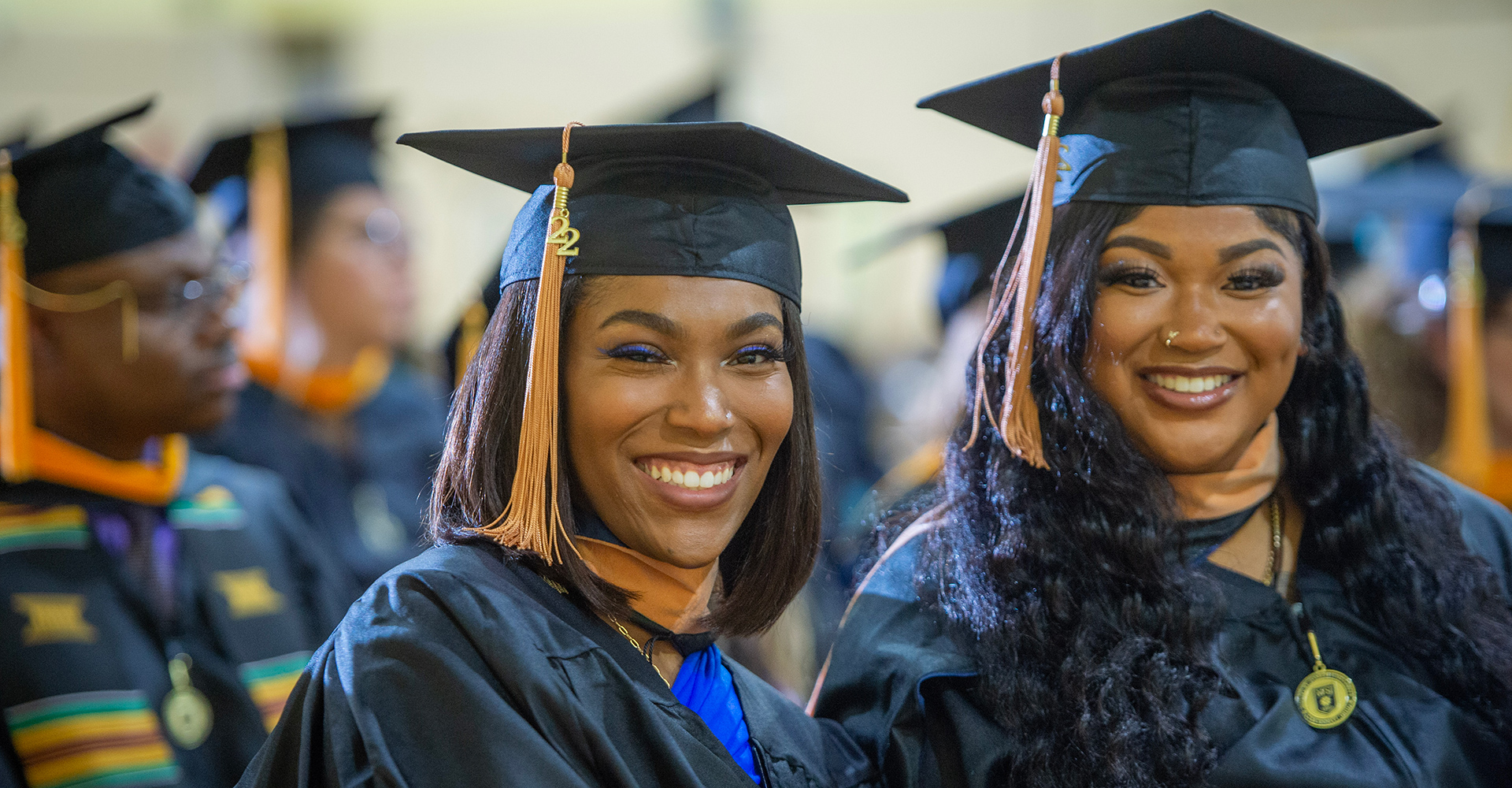 MSJ female students smiling side by side each other in cap and gown during december graduation