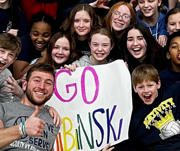 Man poses with a group of students