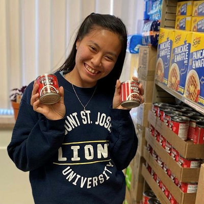 Female student holding canned good smiling