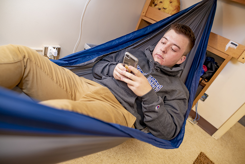 msj male student in hammock in residence hall dorm.