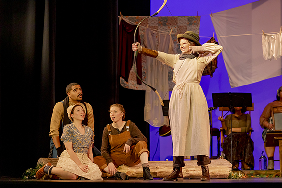 Student actor shooting a bow and arrow during a play