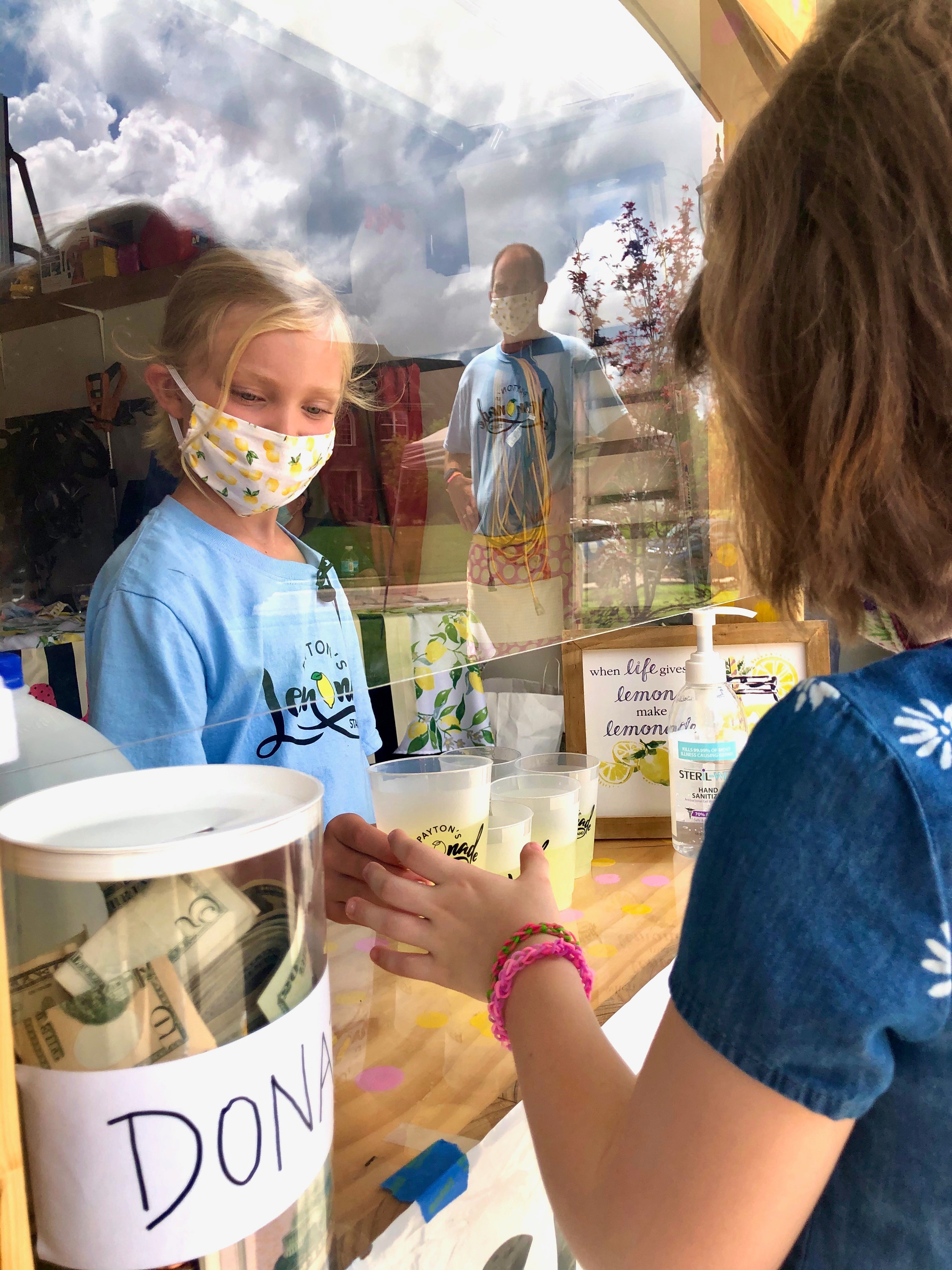 girl handing out lemonade