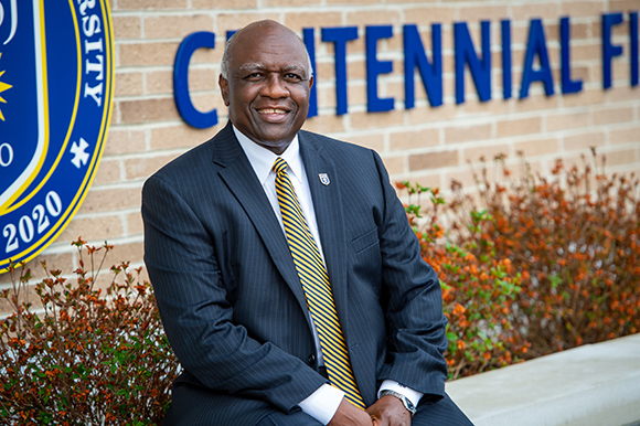 president H. James Williams sitting in front of field house. 